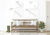 a wooden bench with two white pillows, a potted plant, and a pair of green boots, all set against a white wall with a series of size charts or diagrams displayed above it.